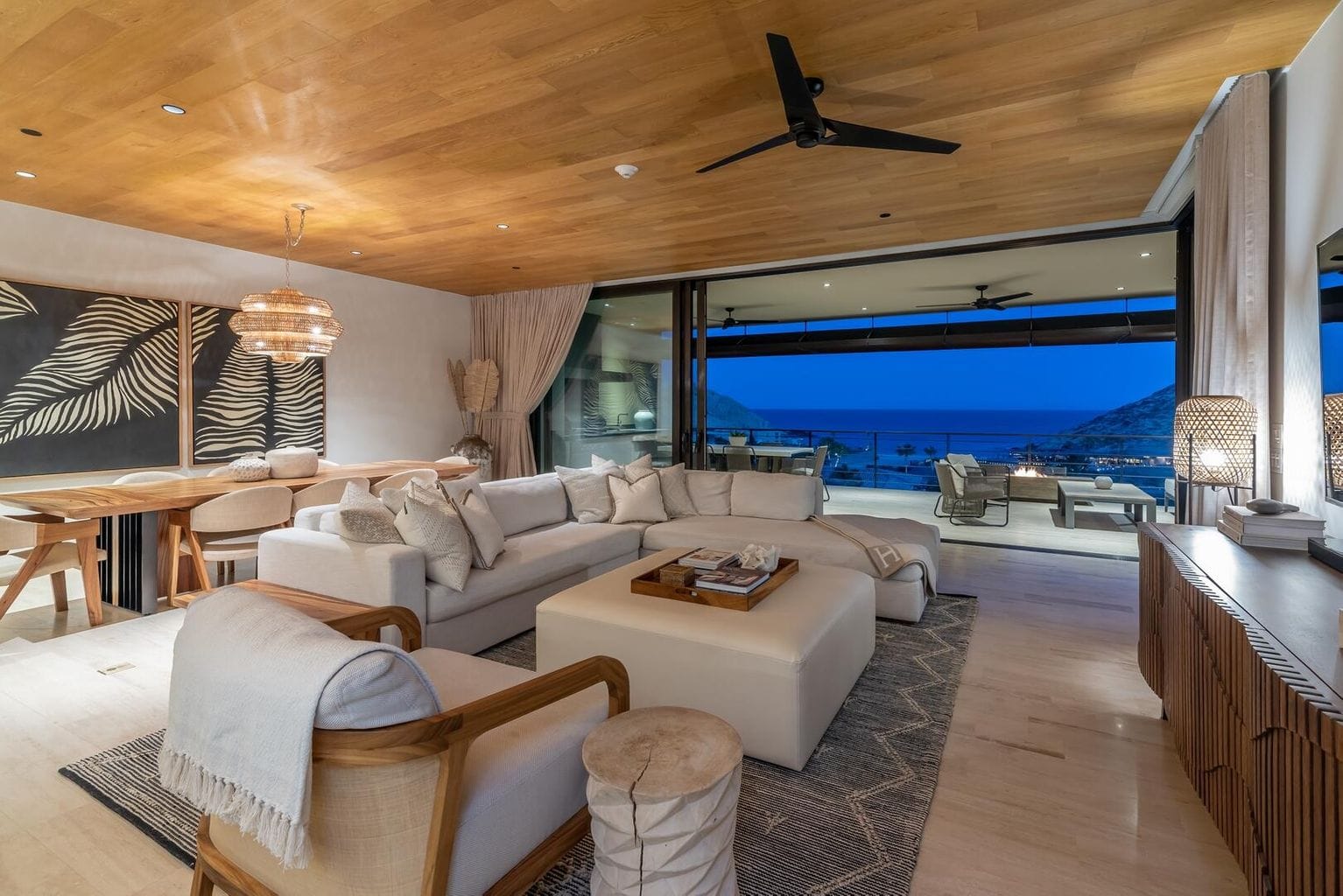 Living room of a Montage residence opening to a terrace over Santa Maria Bay at dusk