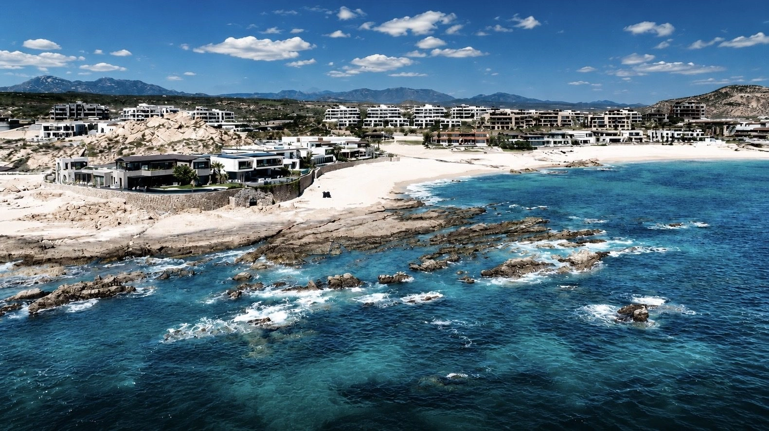 Cabo San Lucas oceanfront real estate — aerial view of beachfront estates and turquoise water