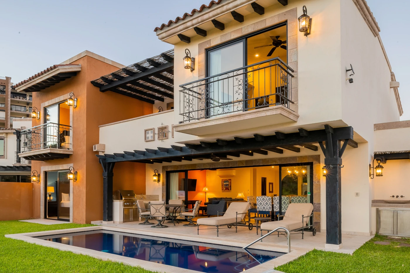 Two-story Copala golf villa at Quivira lit at dusk, with private pool