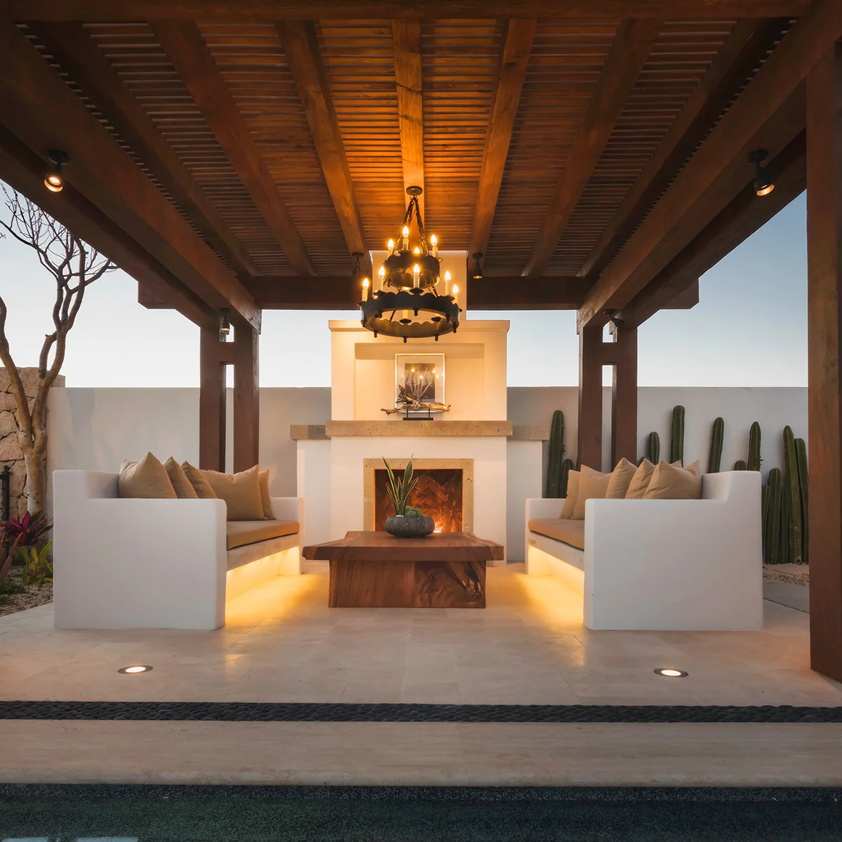 Covered outdoor lounge with fireplace at a Rancho San Lucas home at dusk