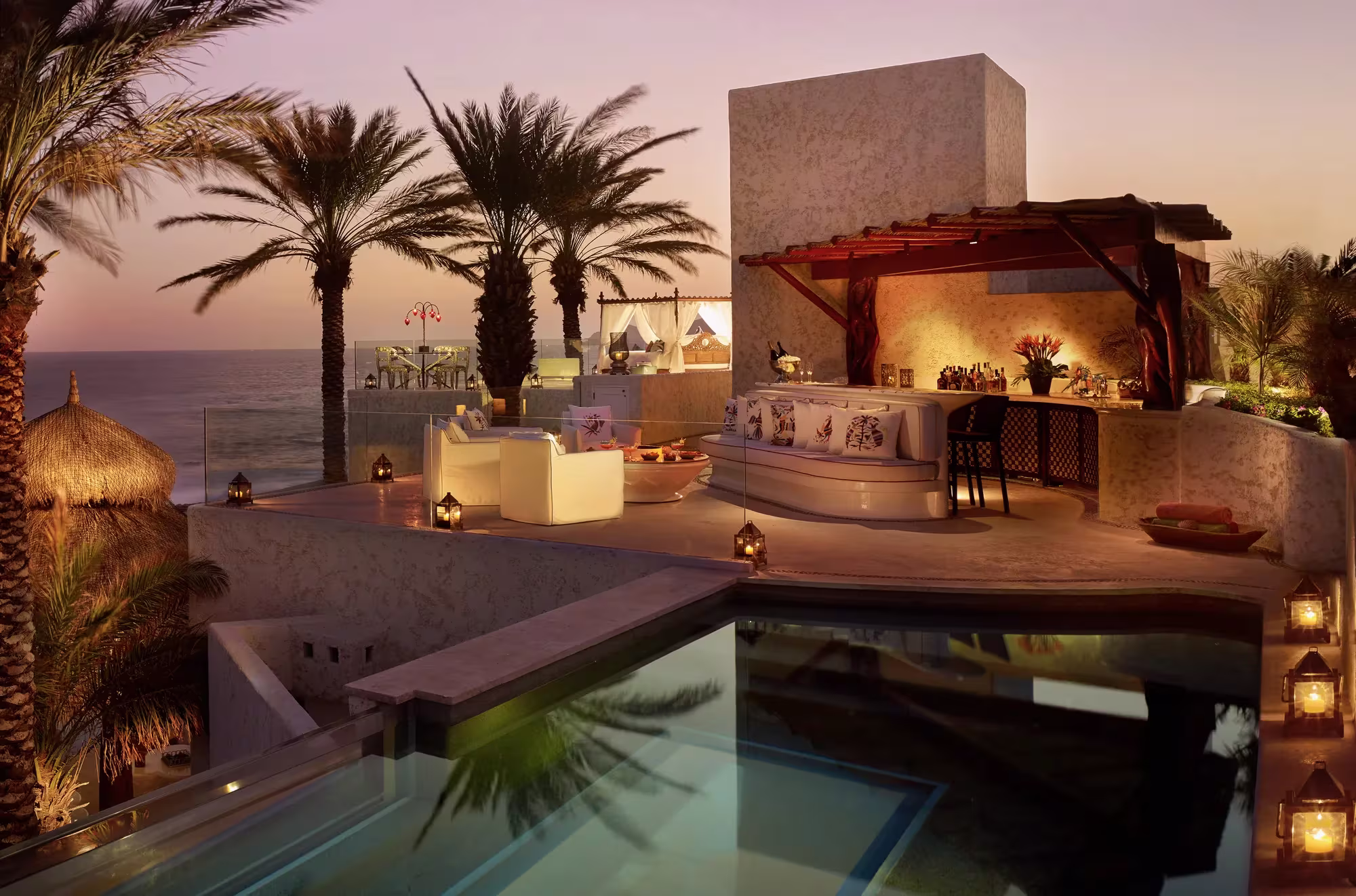 Rooftop terrace of the Ty Warner Mansion at dusk, with its glass-bottom lap pool and bar over the Sea of Cortez