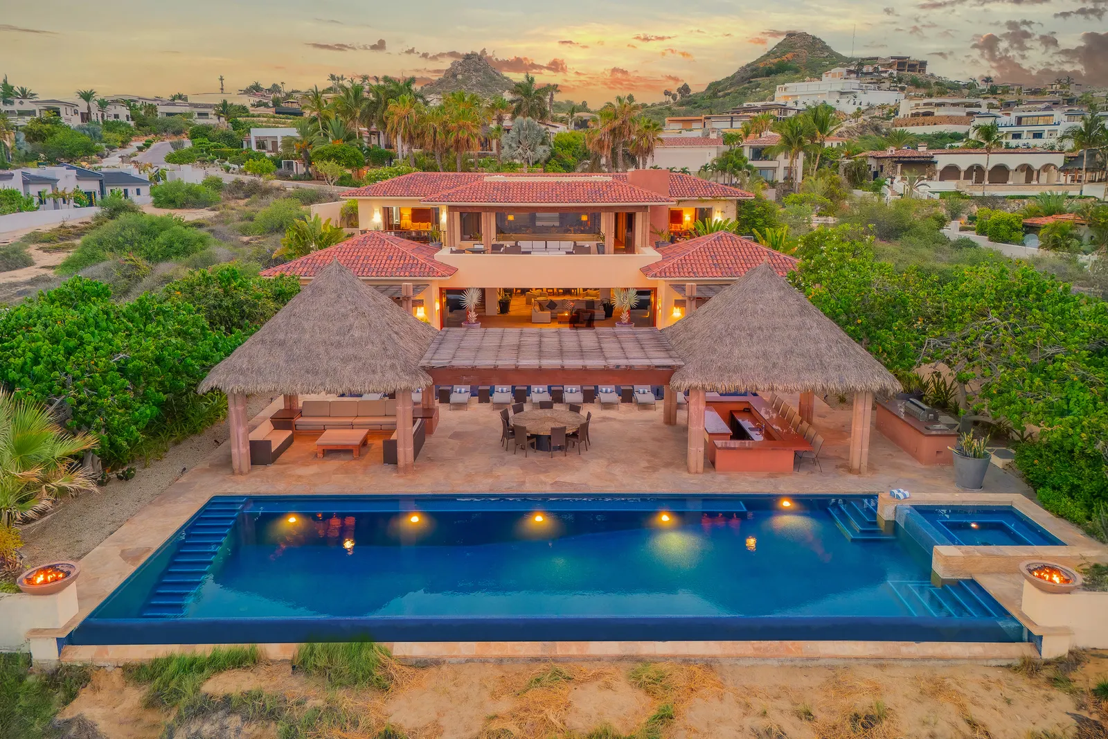 Aerial view of a hillside villa with pool in Puerto Los Cabos at dusk